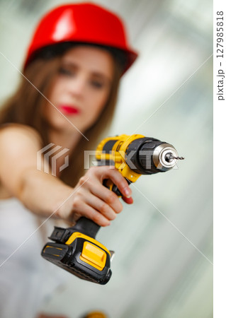 Woman using power driil for work at home 127985818