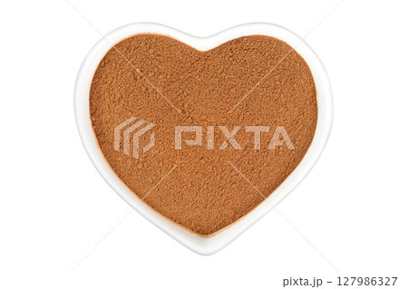 Cinnamon powder in ceramic bowl isolated on white background. Top view. Flat lay. 127986327