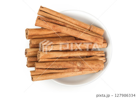 Cinnamon sticks in ceramic bowl isolated on white background with full depth of field. Top view. Flat lay. 127986334