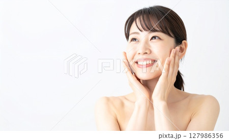 頬に手を添えて微笑む女性のスキンケア 127986356