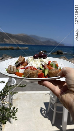 Greek Salad Held by the Sea on a Sunny Day 127986433