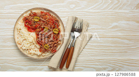 Ropa vieja with white rice, tomato sauce and green olives on a plate top view, traditional dish of Cuba, space for text 127986588