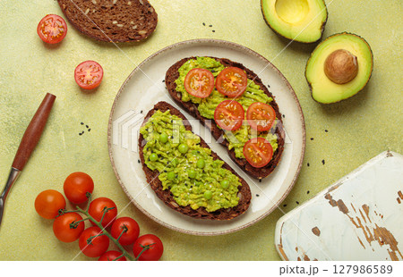 Healthy breakfast with avocado, tomatoes and peas on rye bread top view on light green background Healthy breakfast with avocado, tomatoes and peas on rye bread top view on light green background 127986589
