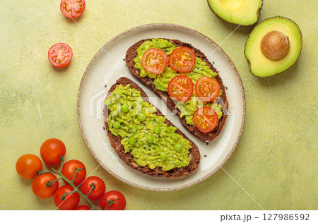 Healthy avocado toast with green peas and cherry tomatoes on whole rye bread top view on light green background Healthy avocado toast with green peas and cherry tomatoes on whole rye bread top view on light green background 127986592