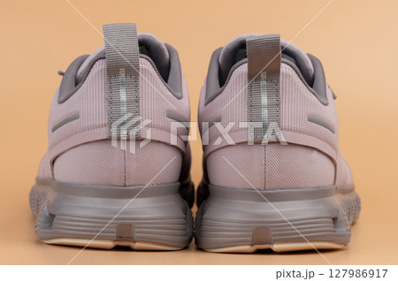 Stylish athletic footwear in soft pink color with gray accents on neutral background Stylish athletic footwear in soft pink color with gray accents on neutral background 127986917