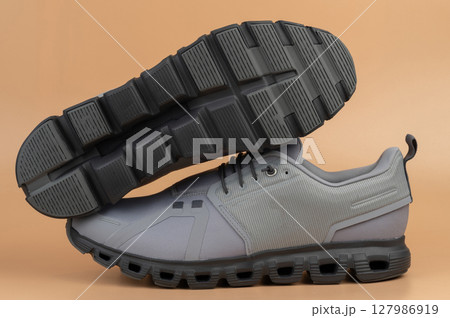 Modern gray athletic shoes with unique sole design on neutral background 127986919