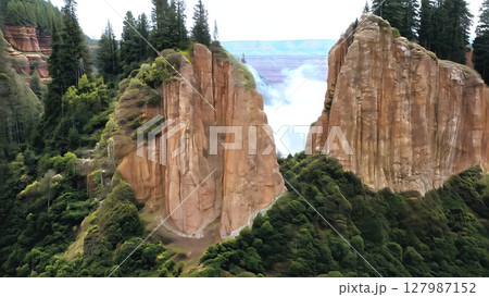 Misty clouds floating over volcanic landscape, unveiling dramatic sandstone cliffs and dense greenery in Conguillio National Park, southern Chile 127987152