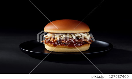 A mouthwatering pulled pork burger sits on a dark plate, showcasing tender meat topped with savory sauce and fresh slaw, perfect for any meal A mouthwatering pulled pork burger sits on a dark plate, showcasing tender meat topped with savory sauce and fresh slaw, perfect for any meal 127987409