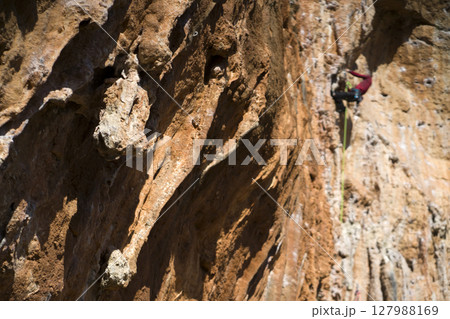 Young man is climbing on the rocks in the mountains. Young man is climbing on the rocks in the mountains. 127988169