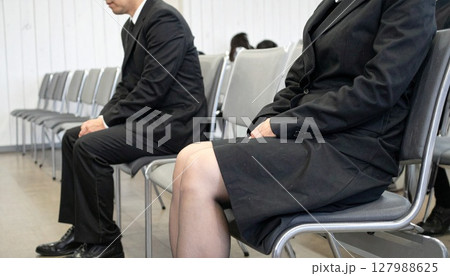 葬儀で静かに座る男女 127988625