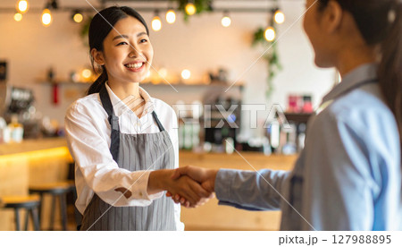 店内で女性と握手するオーナー 127988895