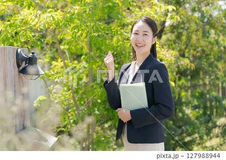 住宅を訪問するスーツの女性 127988944
