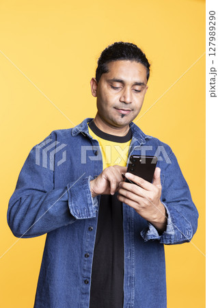 Indian man adding payment method on online website with his card, delighted to take advantage of promotions in the studio. Young person thrilled to do internet shopping, typing credit card data. 127989290