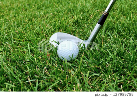 芝生「ラフ」上の白いゴルフボールとサンドウェッジ 127989789