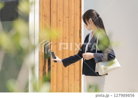 ドアの施錠をするスーツの女性 127989856