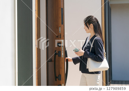 ドアの施錠をするスーツの女性 127989859