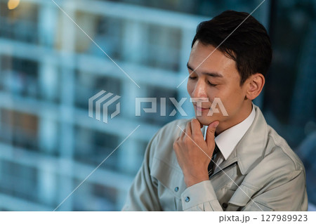 考え事をする作業着の男性 127989923