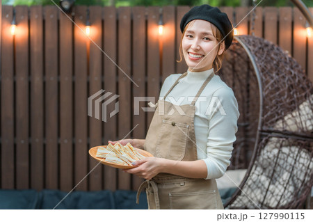 おしゃれなカフェで働くエプロン姿の若いアジア人女性 127990115