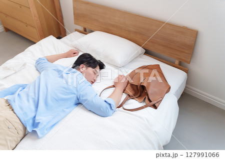 過労でベッドに倒れる男性 127991066