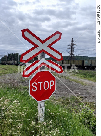 stop sign at railroad crossing near green field with electric poles in background during daytime. 127991320