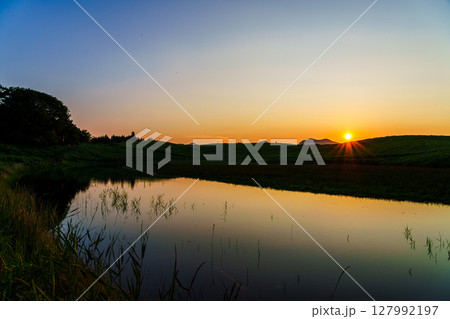 満々と水を湛えたお亀池の向こう曽爾の山並みへ沈んで行く夕日③ 127992197