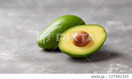 Fresh organic avocado with creamy green flesh and natural pit on textured background for healthy eating Fresh organic avocado with creamy green flesh and natural pit on textured background for healthy eating 127992393