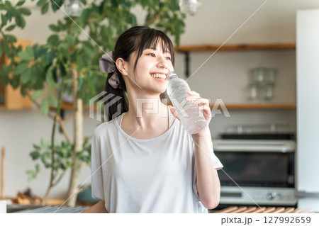 キッチンの前でミネラルウォーター,水,スポーツドリンクを飲む若いアジア人女性 キッチンの前でミネラルウォーター,水,スポーツドリンクを飲む若いアジア人女性 127992659