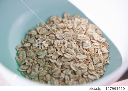 Close-up view of raw oats in a blue bowl on white background 127993620