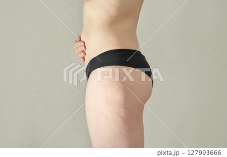 Young adult caucasian female showing side view of body with black undergarment Young adult caucasian female showing side view of body with black undergarment 127993666