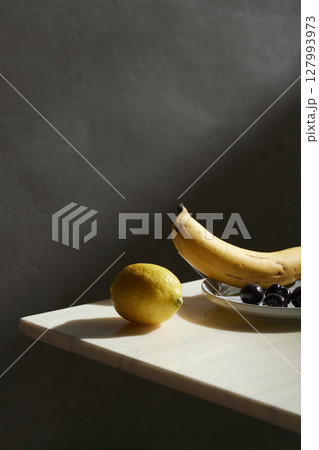 A cozy backdrop with fresh fruits and grass on a table with natural sunlight and shadows. A cozy backdrop with fresh fruits and grass on a table with natural sunlight and shadows. 127993973