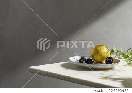 A cozy backdrop with fresh fruits and grass on a table with natural sunlight and shadows. 127993975
