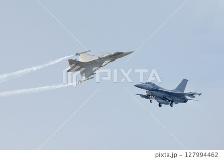 Two fighter planes on a background of white clouds in a blue sky 127994462