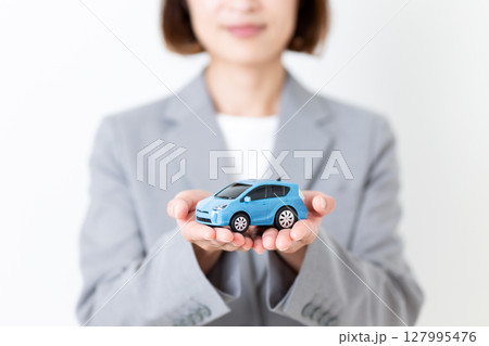 自動車の模型を持つグレーのスーツ姿のミドル女性 127995476