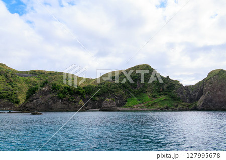ヒリゾ浜渡船に乗って出港するスキンダイバー、シュノーケラー。 青い海と無人島の大根島、岩礁が見える。 127995678