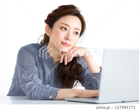 白背景でパソコン作業をする若い女性ビジネスパーソンのポートレート 127995772