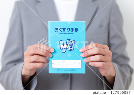 お薬手帳を持つグレーのスーツ姿のミドル女性 127996087