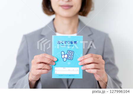 お薬手帳を持つグレーのスーツ姿のミドル女性 127996104