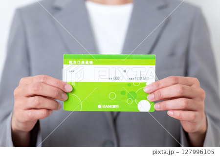 銀行の預金通帳を持つグレーのスーツ姿のミドル女性 銀行の預金通帳を持つグレーのスーツ姿のミドル女性 127996105