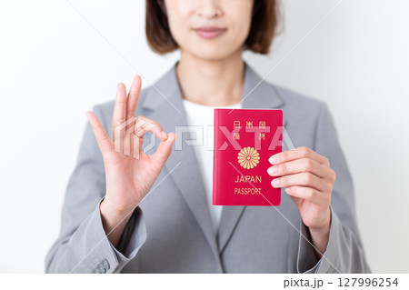 パスポートを持って丸サインをするグレーのスーツ姿のミドル女性 パスポートを持って丸サインをするグレーのスーツ姿のミドル女性 127996254