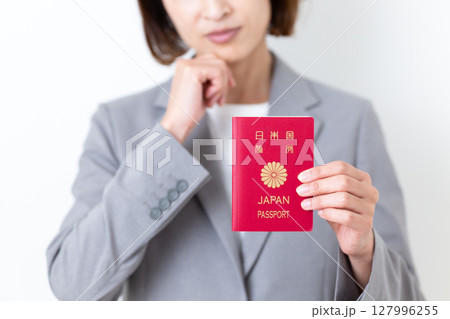パスポートを持って悩むグレーのスーツ姿のミドル女性 パスポートを持って悩むグレーのスーツ姿のミドル女性 127996255
