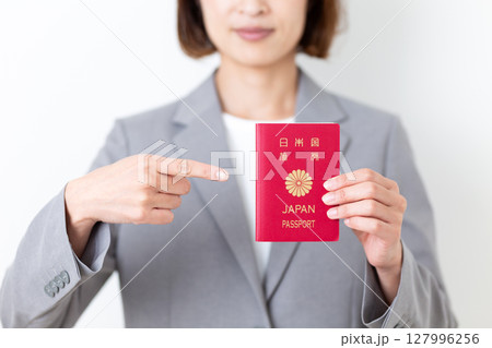 パスポートを指差すグレーのスーツ姿のミドル女性 127996256