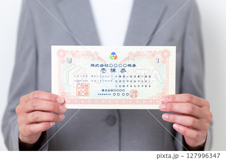 株券を持つグレーのスーツ姿のミドル女性 127996347