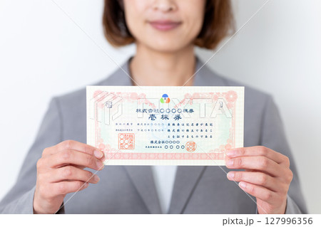 株券を持つグレーのスーツ姿のミドル女性 127996356