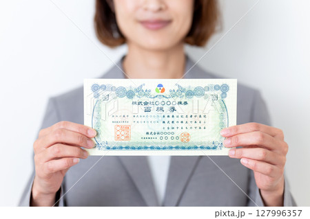 株券を持つグレーのスーツ姿のミドル女性 127996357