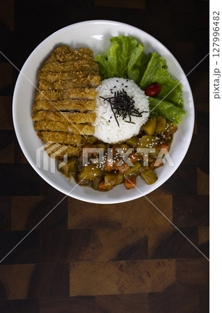 Fried Chicken Curry Rice On A Plate Placed On A Wooden Table, Background for advertising and wallpaper in healthcare and food scene. Fried Chicken Curry Rice On A Plate Placed On A Wooden Table, Background for advertising and wallpaper in healthcare and food scene. 127996482