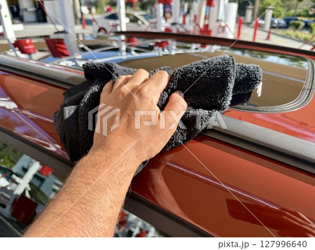 Man hand cleaning car with microfiber cloth at car wash Man hand cleaning car with microfiber cloth at car wash 127996640