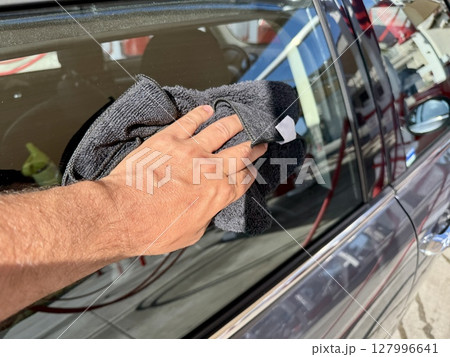 Man hand cleaning car with microfiber cloth at car wash 127996641
