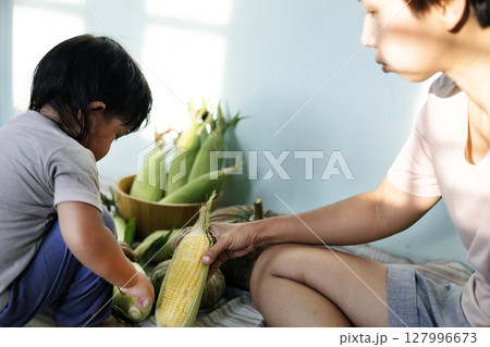 Mother AnD Son Holds Fresh Corn In His Hand, Background for advertising and wallpaper in food and harvest scene Mother AnD Son Holds Fresh Corn In His Hand, Background for advertising and wallpaper in food and harvest scene 127996673