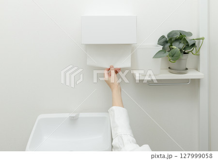 トイレでペーパータオルを使う女性の手 127999058
