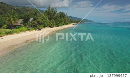 Stunning aerial view of a tropical beach with crystal-clear turquoise water gently lapping against the shore, inviting tourists to swim and relax amidst lush green vegetation and palm trees Stunning aerial view of a tropical beach with crystal-clear turquoise water gently lapping against the shore, inviting tourists to swim and relax amidst lush green vegetation and palm trees 127999457